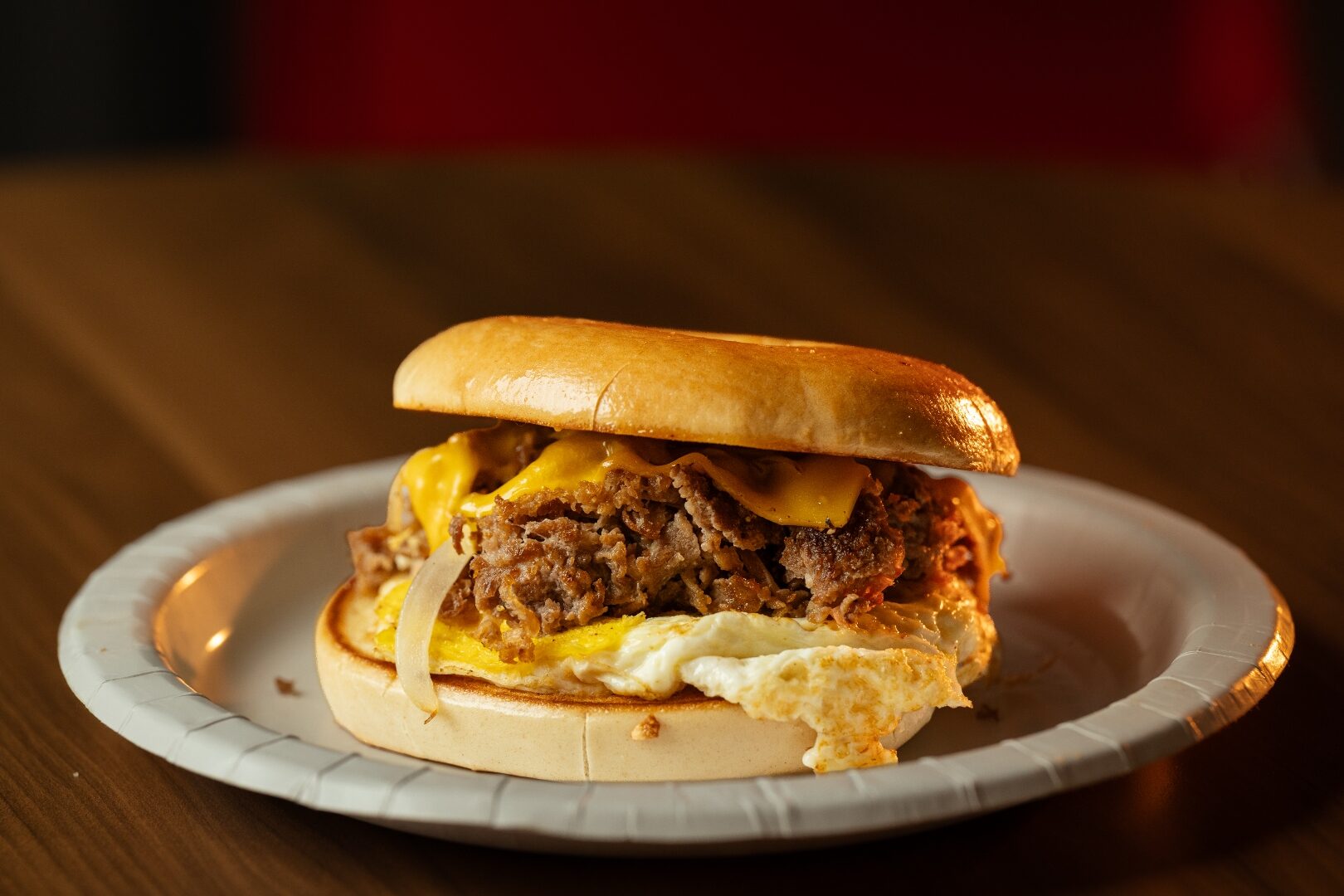 Philly steak breakfast bagel sandwich with melted cheese and fried egg